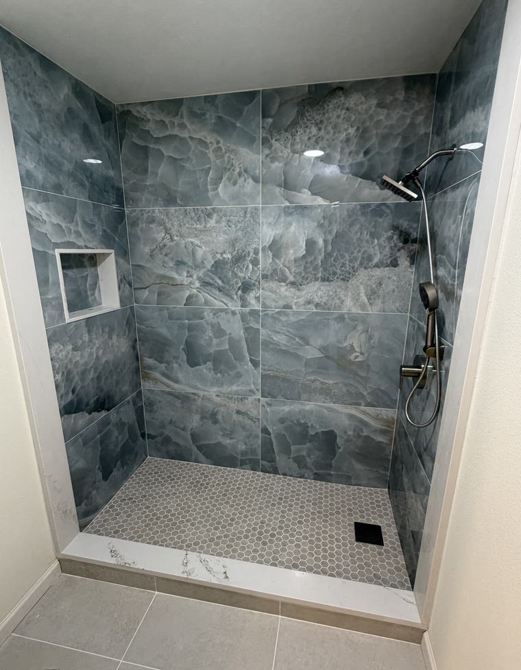 Blue-grey marble slab shower with tile niche and hexagon mosaic floor
