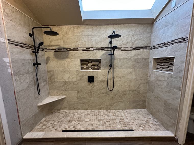 Large double shower with skylight, dual black rain heads, and mosaic niches